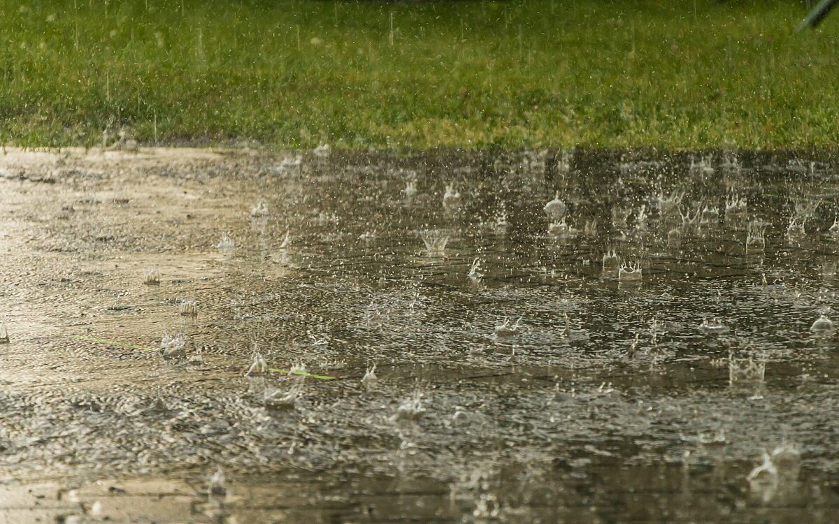 Regen fällt auf nassen Asphalt. Das Wasser steht dort bereits Regen fällt auf nassen Asphalt. Das Wasser steht dort bereits
